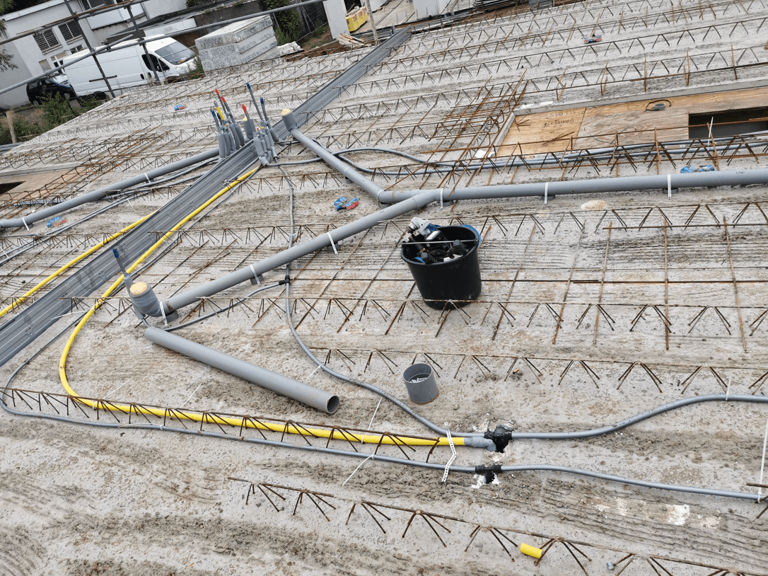 Riool- en waterleidingen aangelegd op de betonvloer van een nieuwbouwwoning